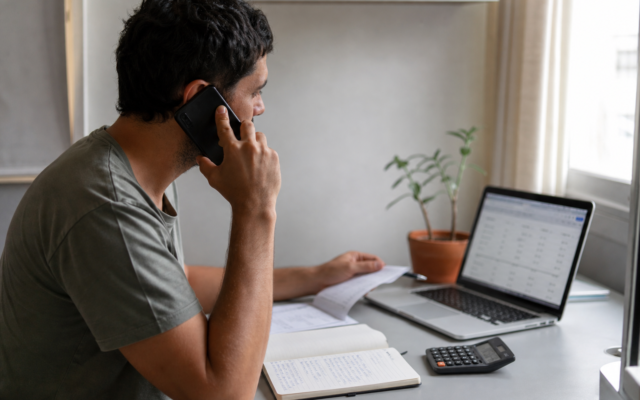 Pessoa ao telefone negociando dívidas com anotações sobre a mesa